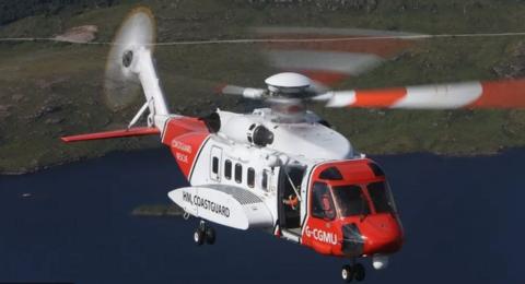 A red and white Coastguard helicopter with its propeller spinning in the air