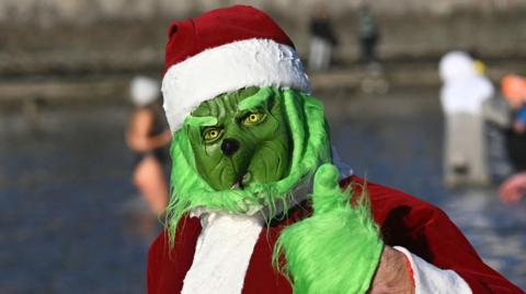 A person dressed as the Grinch for a swim