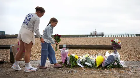 A woman and girl lay flowers near the beach in West Sussex