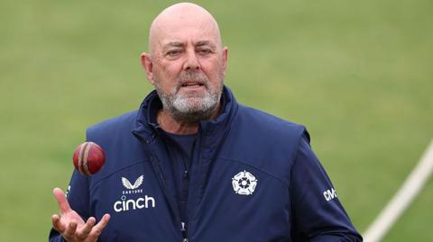 Darren Lehmann standing on a cricket pitch holding his right hand out ready to catch a cricket ball