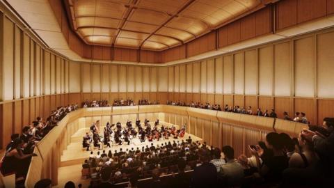 An artist's impression of the concert hall with an orchaestra playing to a packed audience watching the performance, with some clapping.