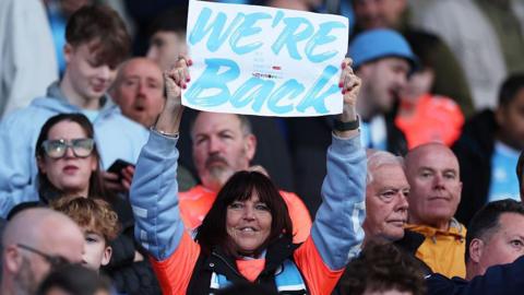Coventry City fan holding up a sign reading We're Back