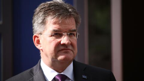 Miroslav Lajčák wears a suit, white shirt and purple tie.