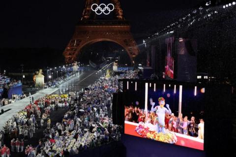 Delegations arrive at the Trocadero as spectators watch French singer Philippe Katerine performing on a giant screen during the opening ceremony of the Paris 2024 Olympic Games on 26 July 2024 