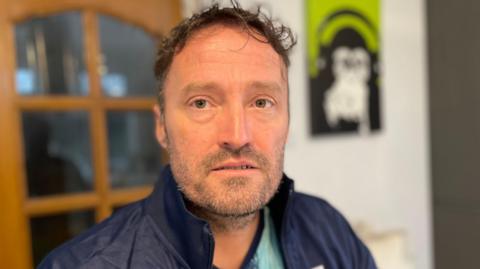 Man in his forties with a blue jacket and short hair