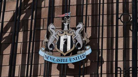 The Newcastle United crest on the black gates of St James' Park.