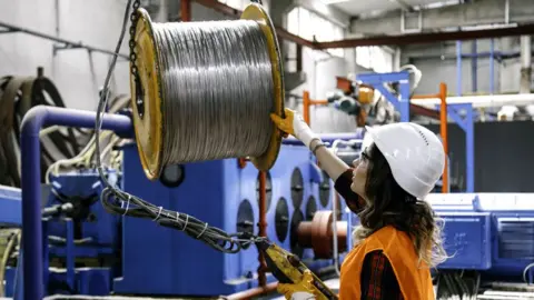 A woman working with metal in a factory