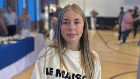 Girl with long blonde hair wearing white sweatshirt