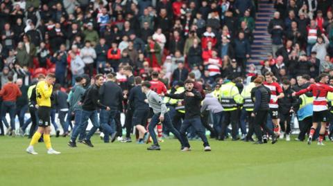 Doncaster Rovers' fans flock on to the pitch after their fourth goal completed a 4-2 win, having been 2-0 down, during the League Two match between Doncaster Rovers and Barrow at the Keepmoat Stadium in Doncaster, on April 20, 2024