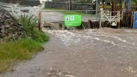 Flood water flows over a submerged rail track