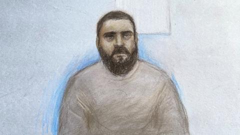 Court artist sketch of Mohammad Bashir. It shows man with short cropped black hair and a dark beard. He is wearing a light grey sweatshirt. 