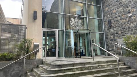 Guernsey's Royal Court - a building with a glass revolving door and glass facade with the crest of the royal court on it. 
