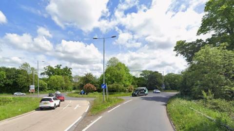 Bolham roundabout screenshot taken from Google Maps. The roundabout is pictured on a sunny but cloudy day with several cars in the shot. There are trees on the roundabout and on both sides.