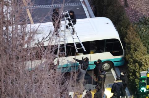 Officers try to climb over busses using ladders at the President's residence