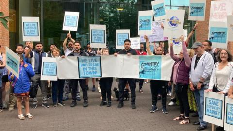People holding banners that include the words save Coventry market and we live and trade in this town.