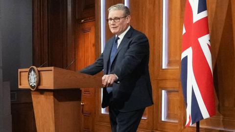 Prime Minister Keir Starmer stands behind a podium and speaks during a press conference at Downing Street on April 1, 2026 in London, England.