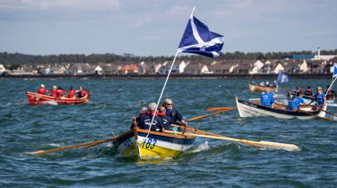 Rowing crews at the Skiffie World Championships are out on the waters at Loch Ryan one of them with a Scottish flag flying