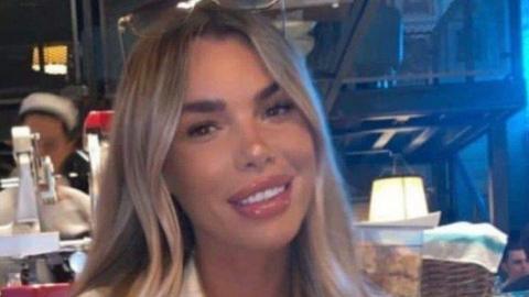 Ashley Dale, who has long, straight blonde hair, smiles at the camera while sitting at a table in restaurant. 