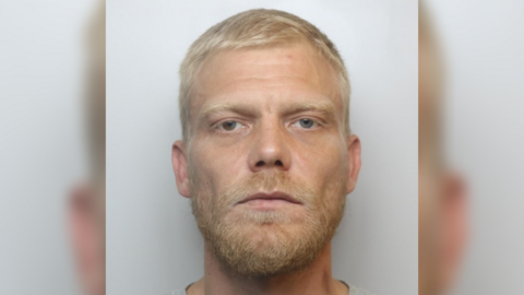 A mugshot of Craig Coney, he has blonde hair and beard and blue eyes