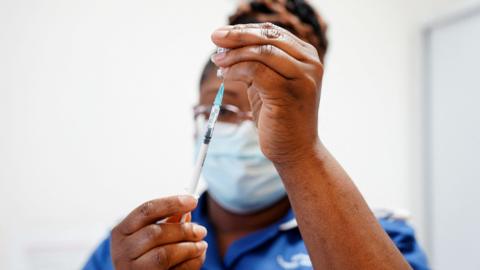 A nurse draws up a dose of vaccine into a syringe