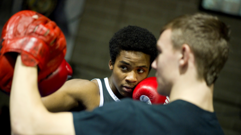 Boys boxing in a ring wearing red gloves