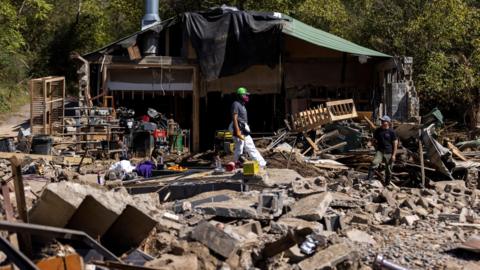 A resident walks through debris following the passing of Hurricane Helene, in Marshall, North Carolina, 8 October 2024