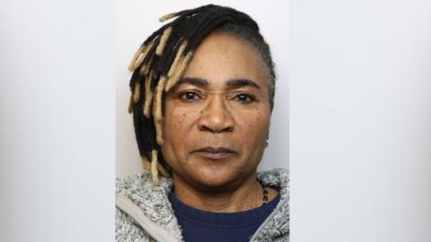 A woman in a mugshot looking seriously at the camera.