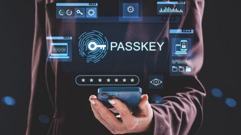 A hand holding a smartphone, with computer-generated holograms showing the word 'passkey'