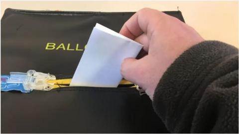 A voting slip being posted into a ballot box
