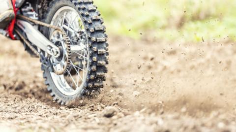 Back wheel of a motocross bike kicks up dirt on a track.