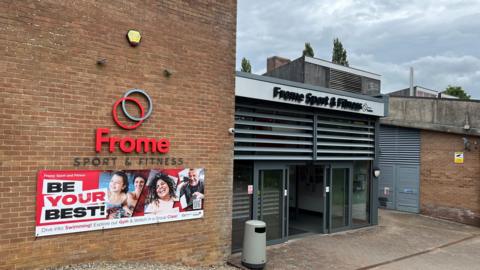 Entrance of Frome Sport & Fitness centre. It's a bricked building with a huge sign above the double doors.