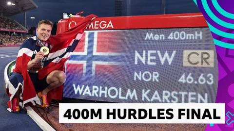 Karsten Warholm poses with the board that indicates his Championship record, with his gold medal in hand and the Norway flag wrapped around him