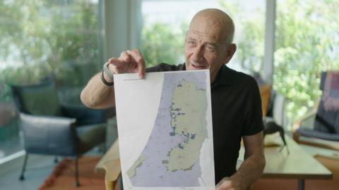 Former Israeli Prime Minister Ehud Olmert holding up his proposed map of Israeli and Palestinian states, as part of a two-state solution