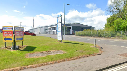 An industrial estate with a grassy patch in front and two signs