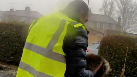 A man in a hi-vis jacket holding a cat