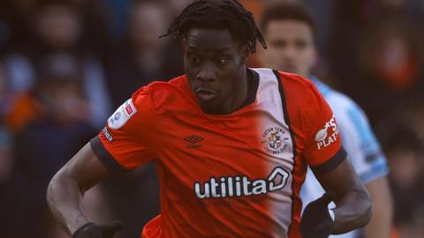 Elijah Adebayo playing for Luton Town in an orange shirt with a white stripe