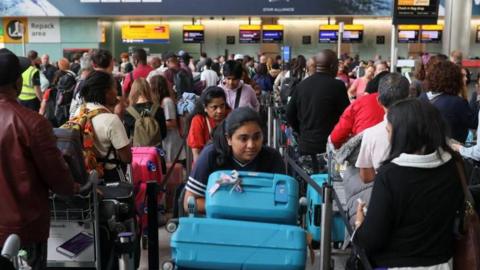 Passengers wait in line at Heathrow Airport, after radar failure led to the suspension of outbound flights across the UK