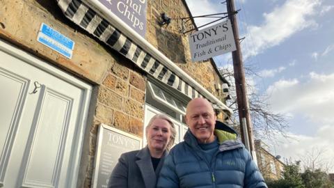 Helena and Robert Hatt stood outside the entrance to Tony's Fish and Chips. Helena has long blo