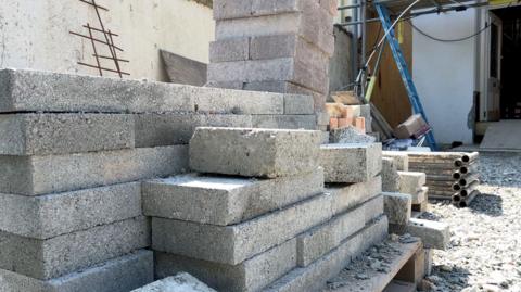 A stack of grey bricks on a pallet at a building site.