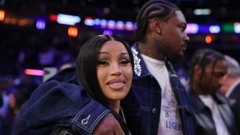 NFL Player Stefon Diggs wraps his arm around his girlfriend, rapper Cardi B, at a basketball game.