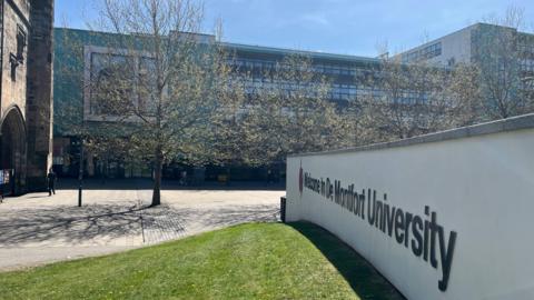 An image of the De Montfort University sign in front of a large building.  