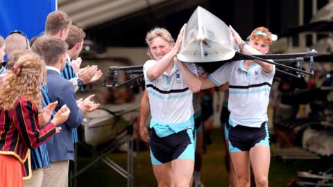 People cheer on the crew of Edinburgh University as they make their way towards the water on the opening day of the 2024 Henley Royal Regatta alongside the River Thames, in Henley-on-Thames.