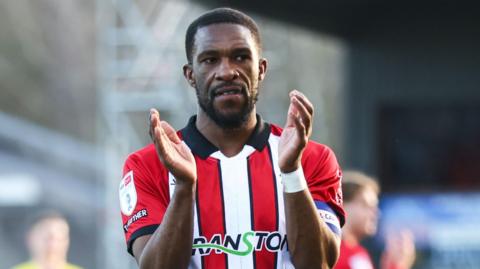 Tendayi Darikwa applauds the Lincoln City fans