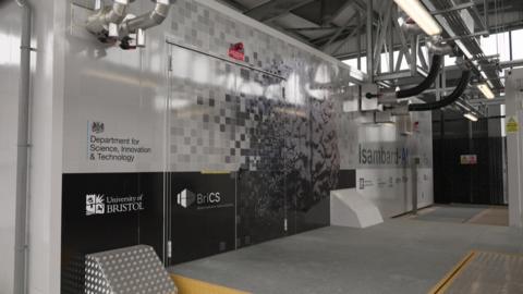 An external view of the Isambart AI computer. There is a doorway in the middle to the computer itself, and various pipes coming out of the wall