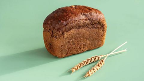 A loaf of brain and some grains on a green background