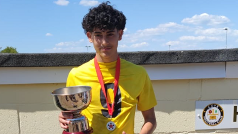 Luis Gabriel Guembes holding a football trophy and wearing yellow football shirt.