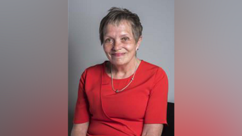 Sue Roberts wearing a red dress in an official party photograph