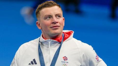 Adam Peaty looks into the crowd with his medal around him