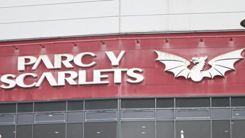 Parc y Scarlets sign and Scarlets logo on outside of stadium in Llanelli