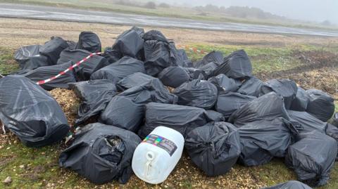 Dozens of black sacks of waste at the side of a country road in the New Forest.